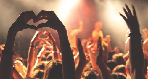 Un photo d'un concert, qui montre des mains étant formés d'un cœur.