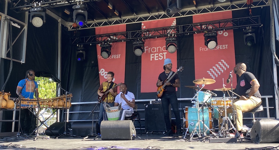 Cinq Musiciens sur une scène, une affiche inscrit Franco Fest