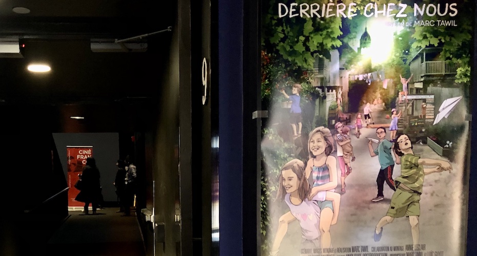Affiche du film Derrière Chez Nous, à côté de l'entrée d'une salle de cinéma sombre,où se trouve un afficeh rouge avec inscrit en blanc CinéFranco!
