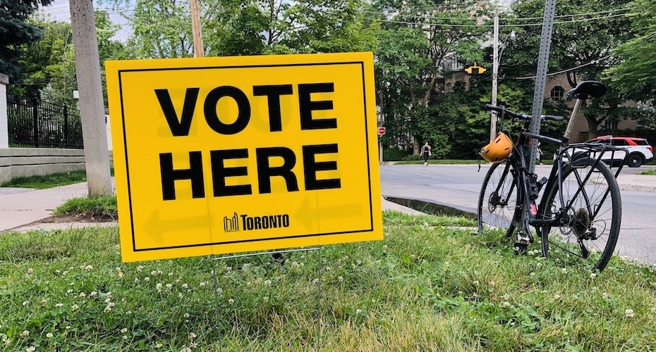 Panneau VOTE HERE jaune planté sur l'herbe verte