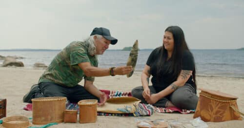 Deux personnes assises sur le sable regarde des outils traditionnels